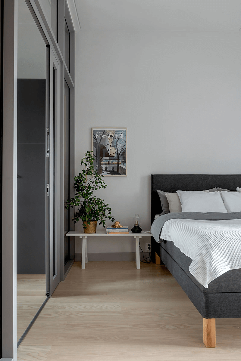 this is a Scandinavian bedroom with a simple double bed and art on the wall in a grey accent feel