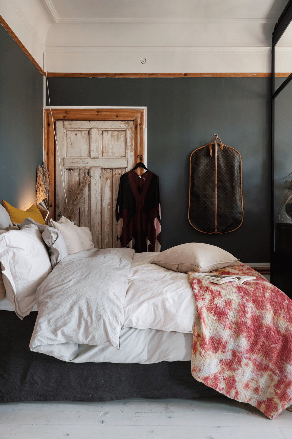 this is a wooden styled Scandinavian apartment with a bedroom that has clothes hanging and textured bedding